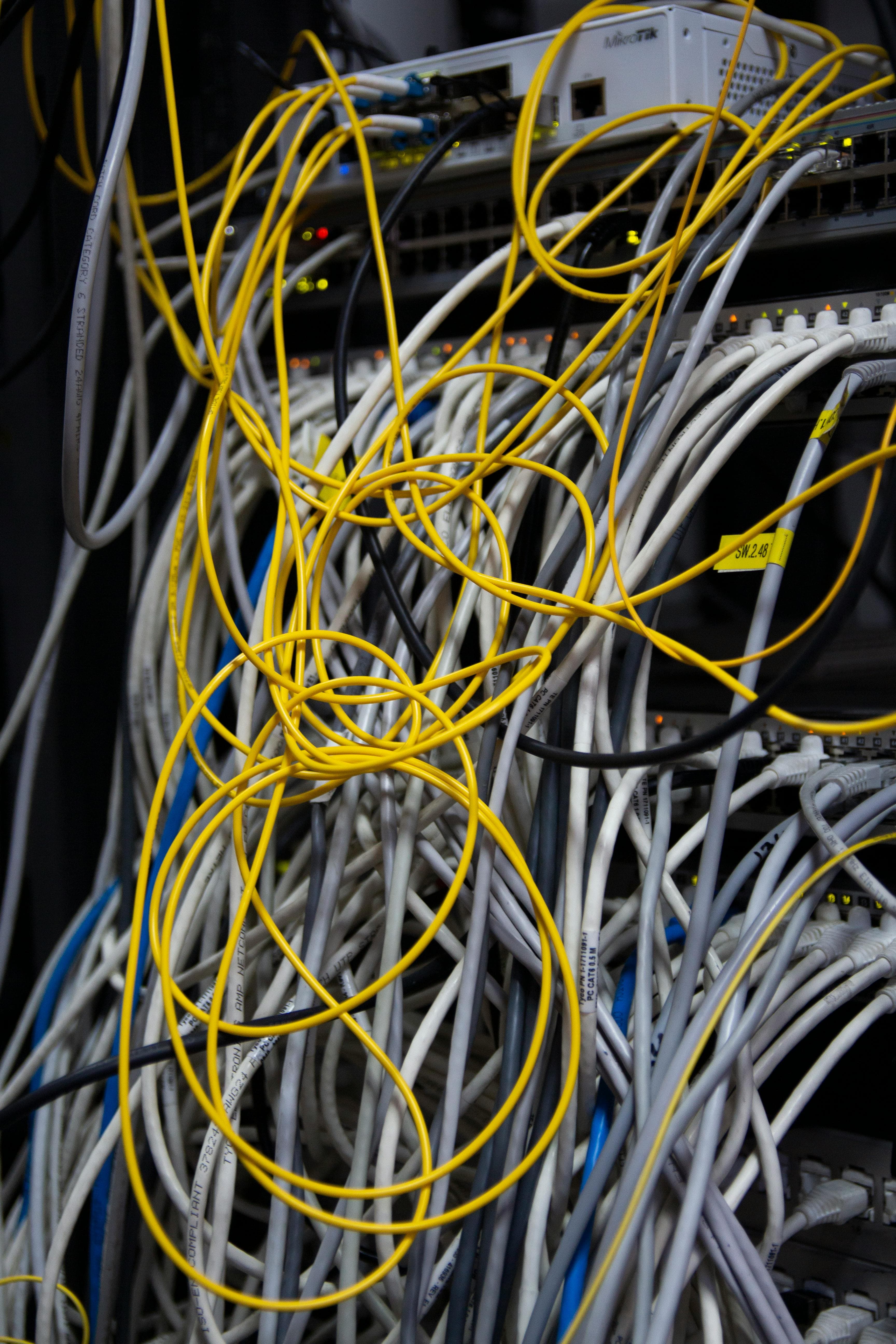Network rack with many yellow and white patch cables
