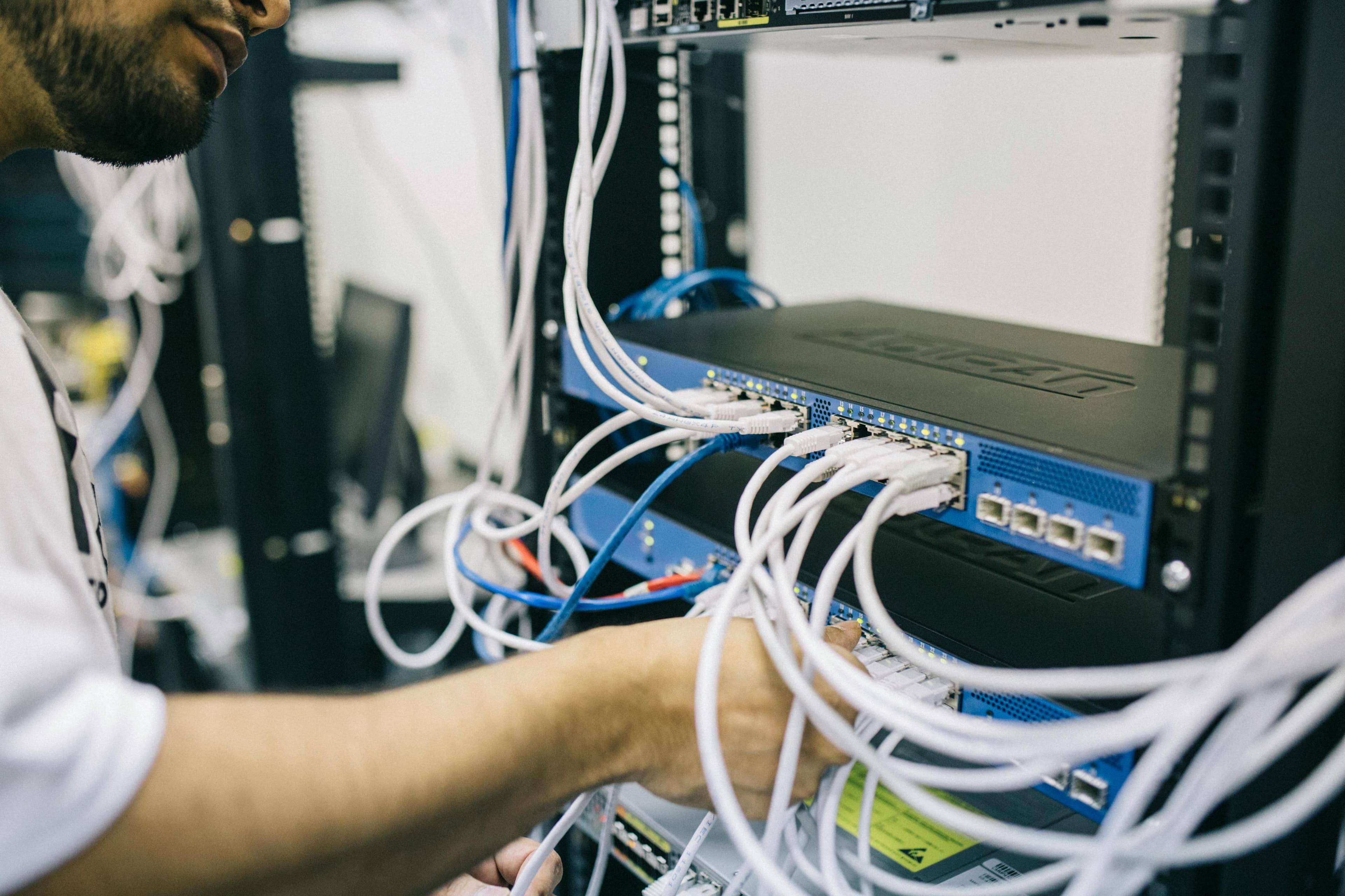 Engineer working with cables and network equipment in a server rack