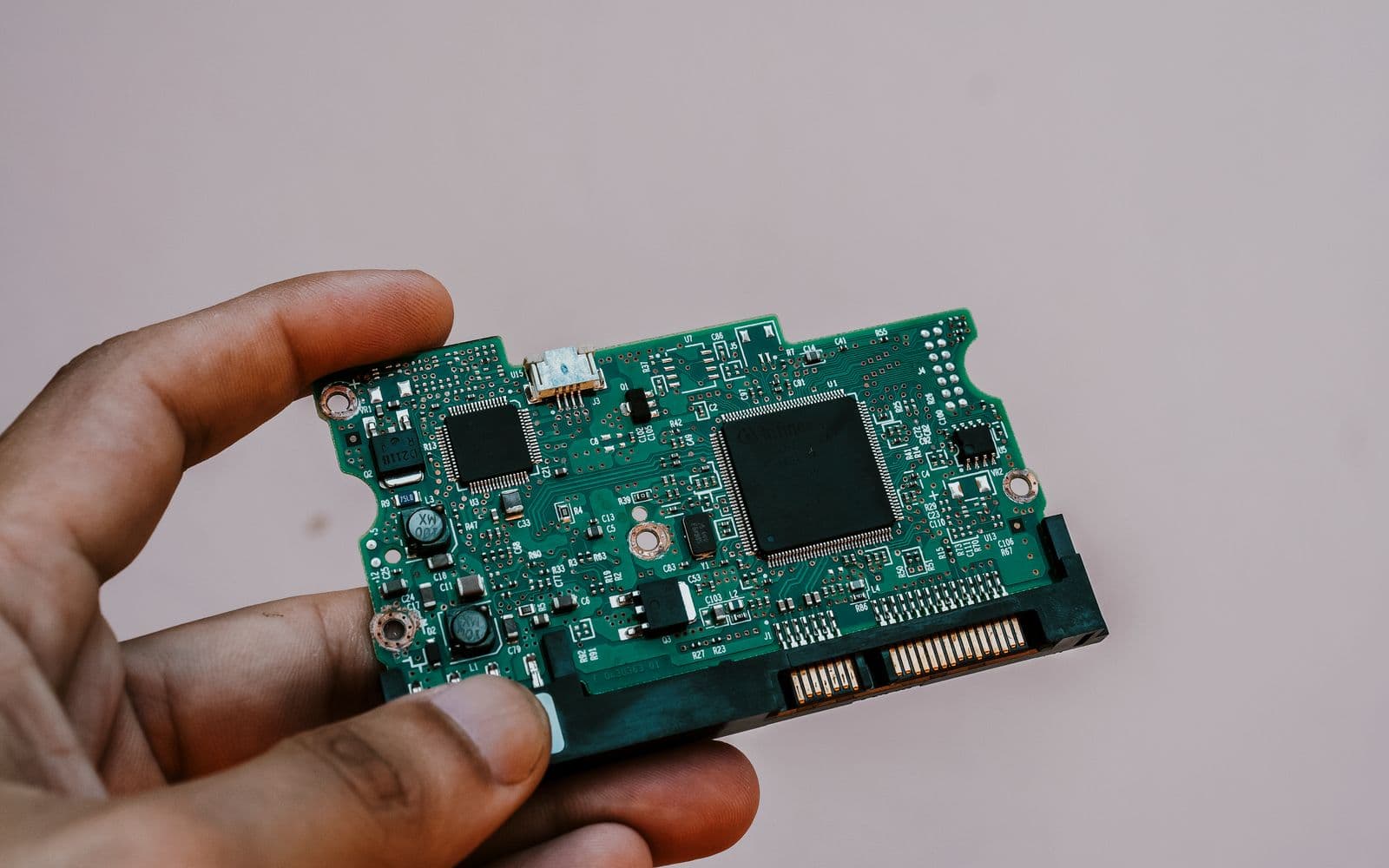 Hand holding a circuit board removed from a storage drive