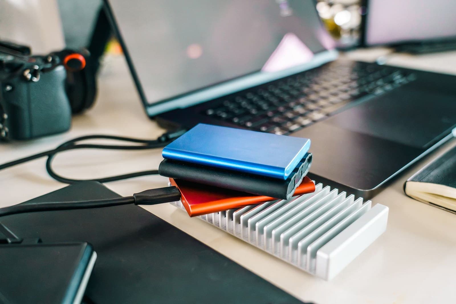 Several external drives in different enclosures beside a laptop