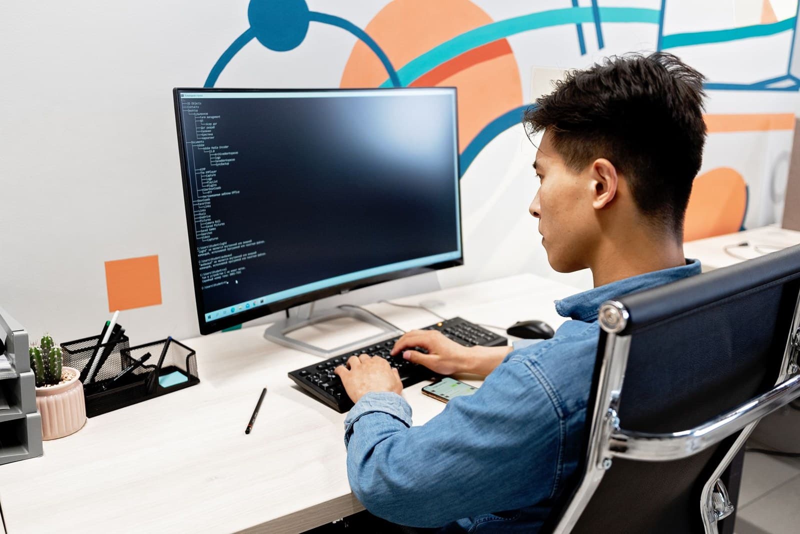 Man at a keyboard facing a monitor with a Windows command prompt open