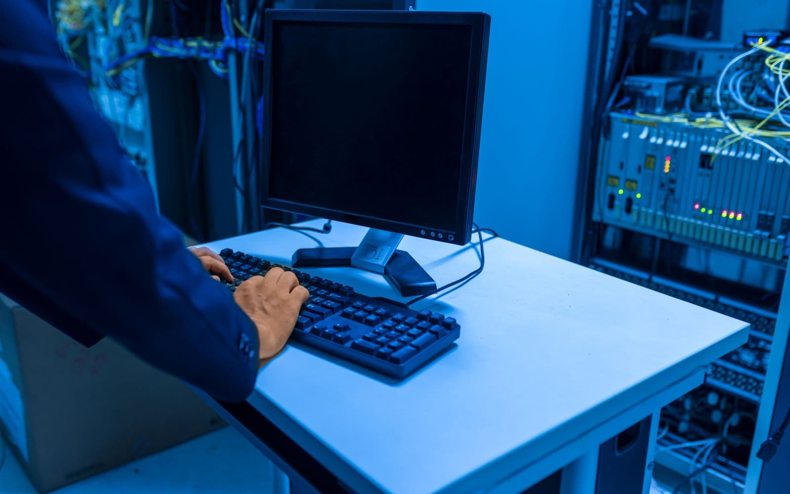 Technician working at a workstation between server racks