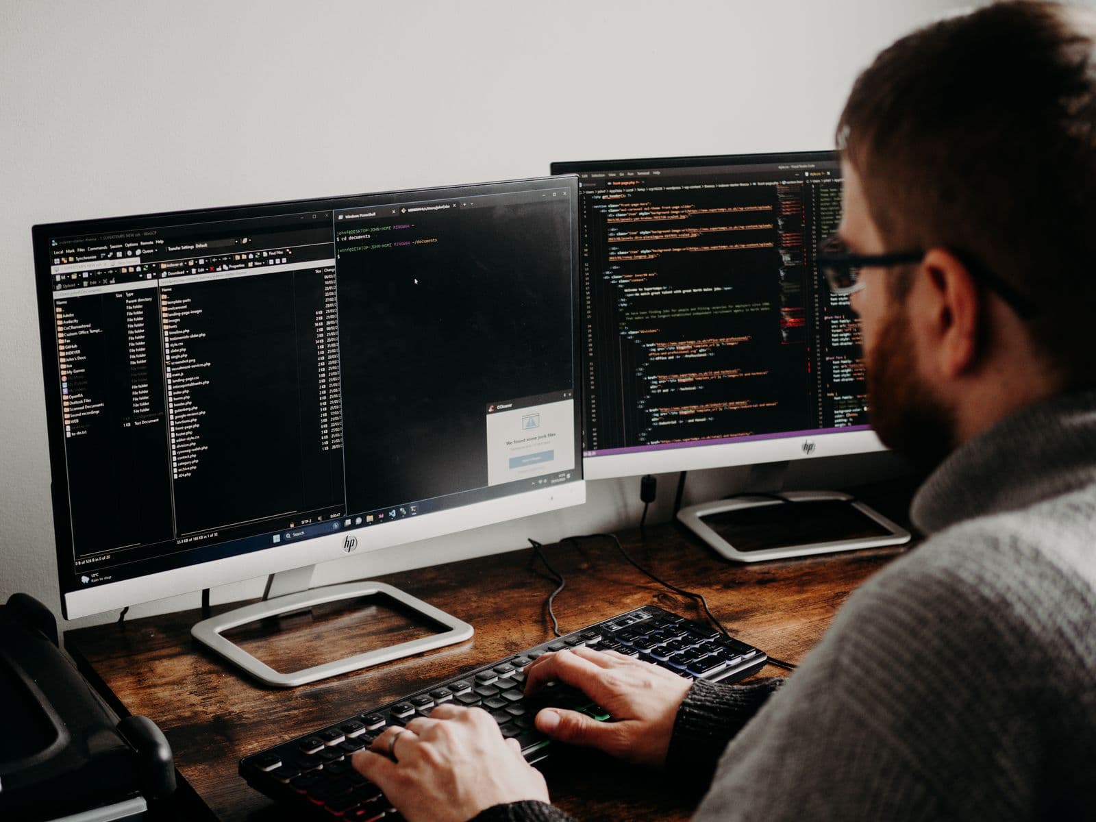 Datenbanktechniker bei der Prüfung von Code auf zwei Bildschirmen für einen Artikel über automatische Plankorrektur