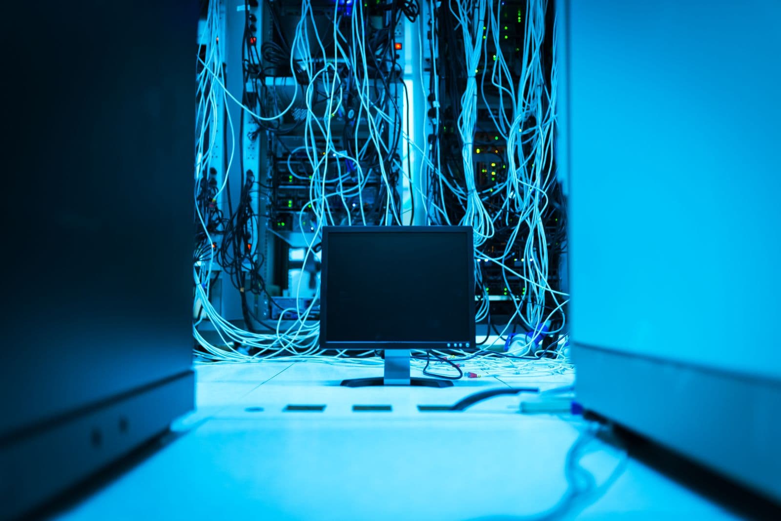 Monitor vor dicht verkabelter Netzwerkinfrastruktur in einem Technikraum
