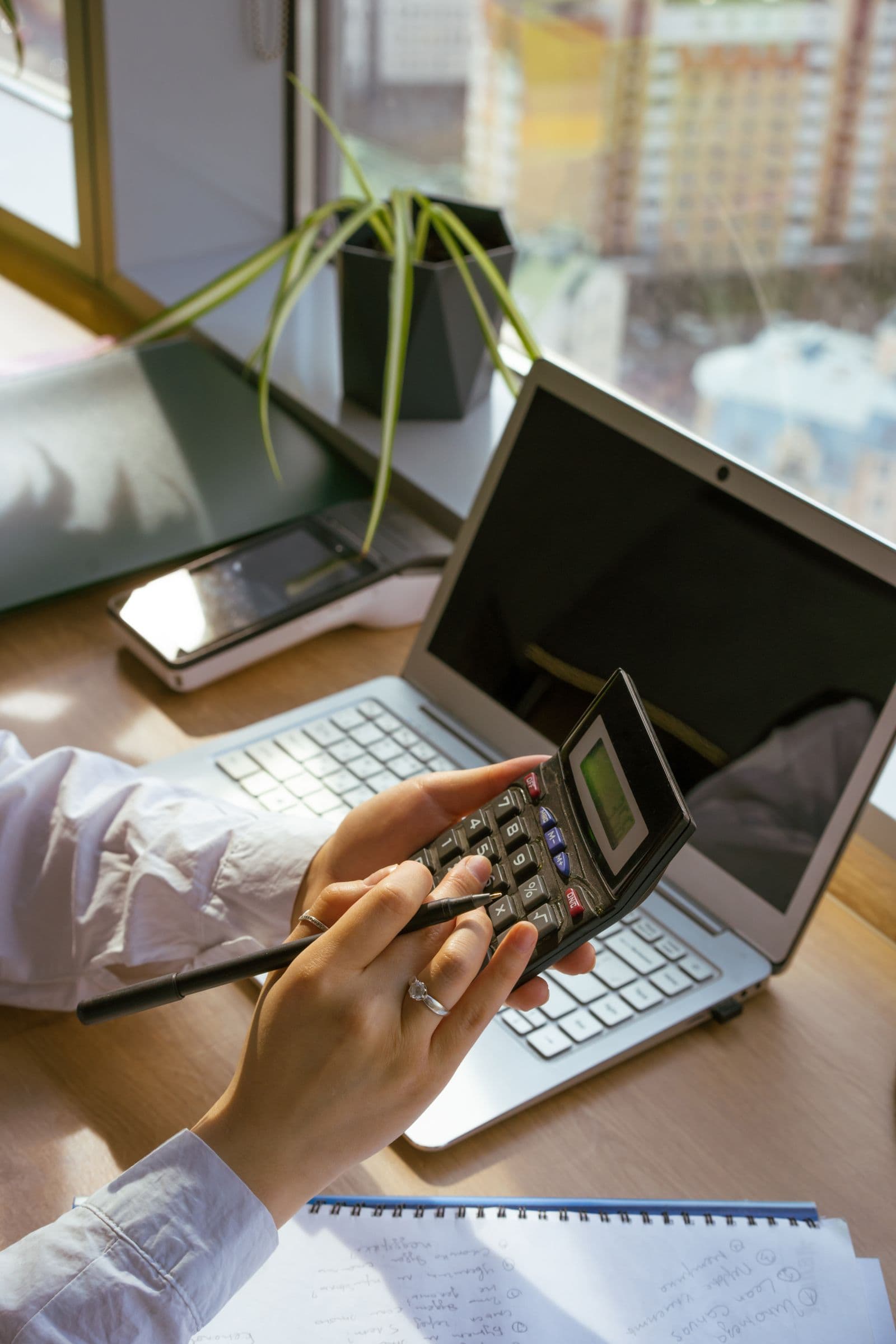 Person prüft Zahlen und Statusinformationen an einem Laptop